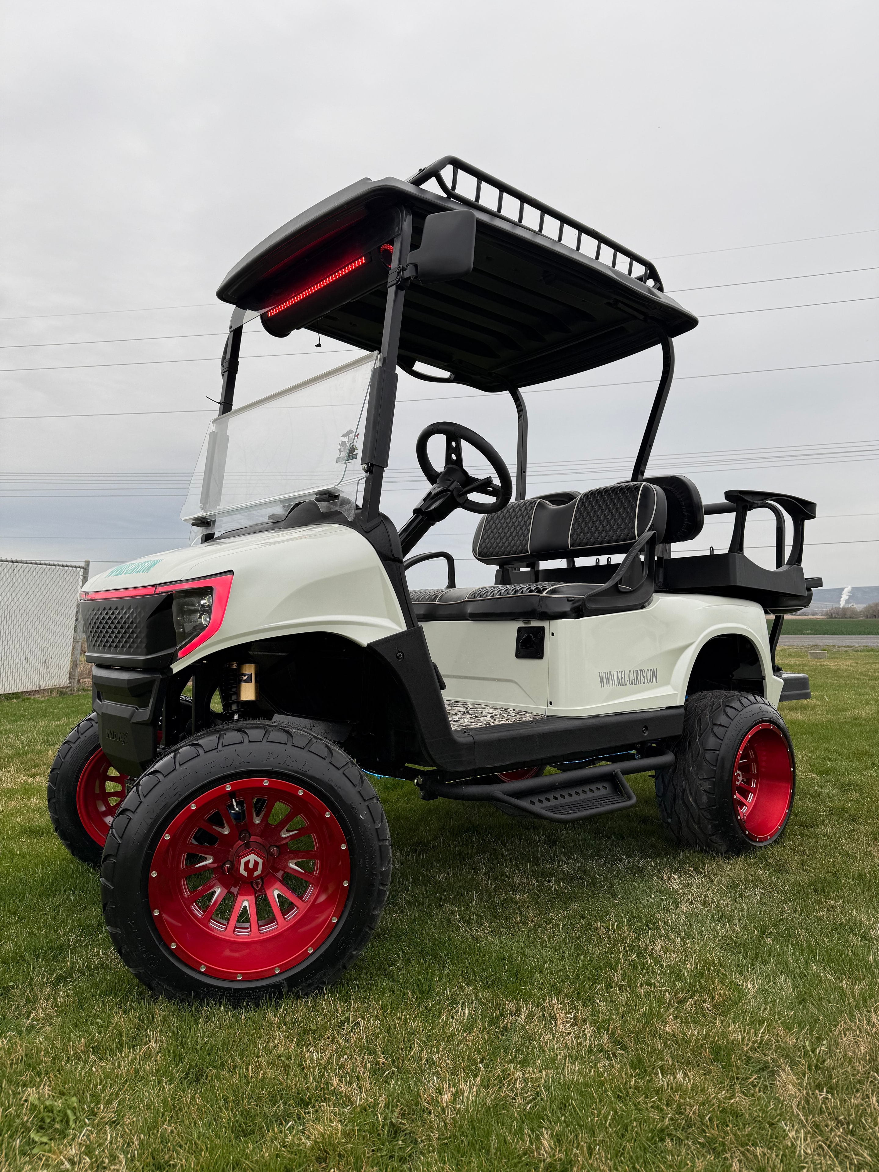 Cream custom golf cart with red wheels and black roof rack