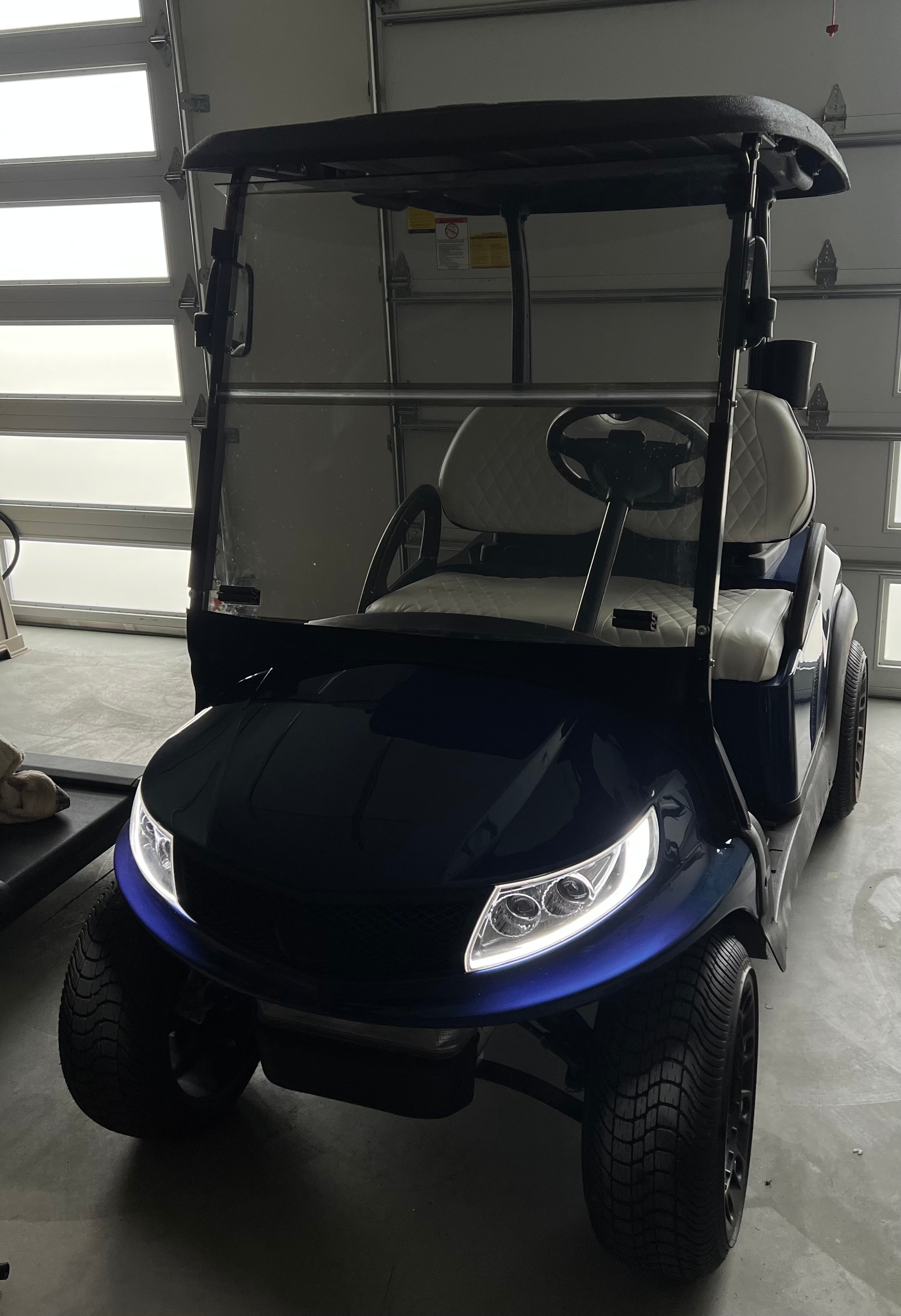 Dark blue custom golf cart with white seats indoors
