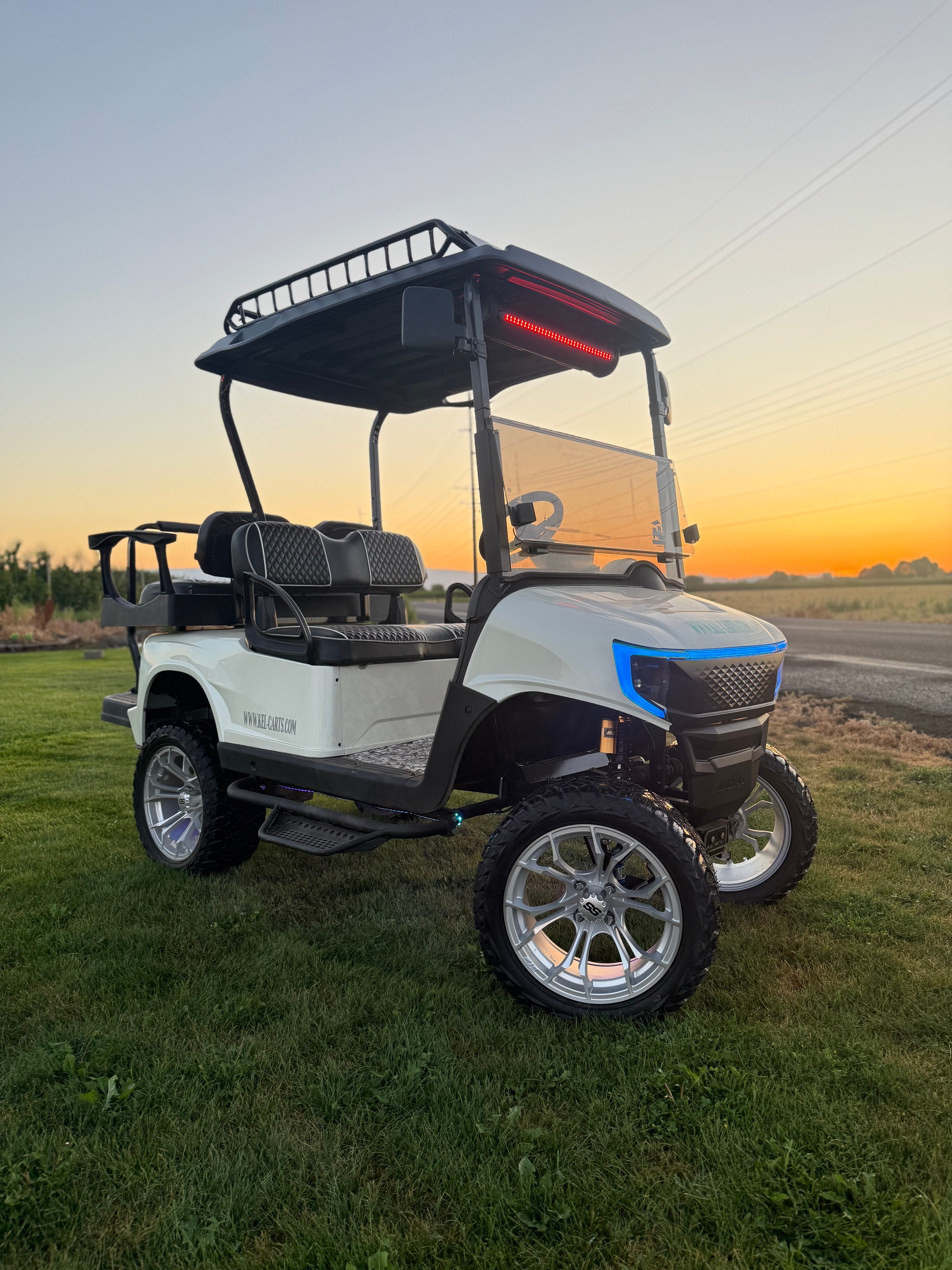 White lifted custom golf cart with blue accent lighting at sunset