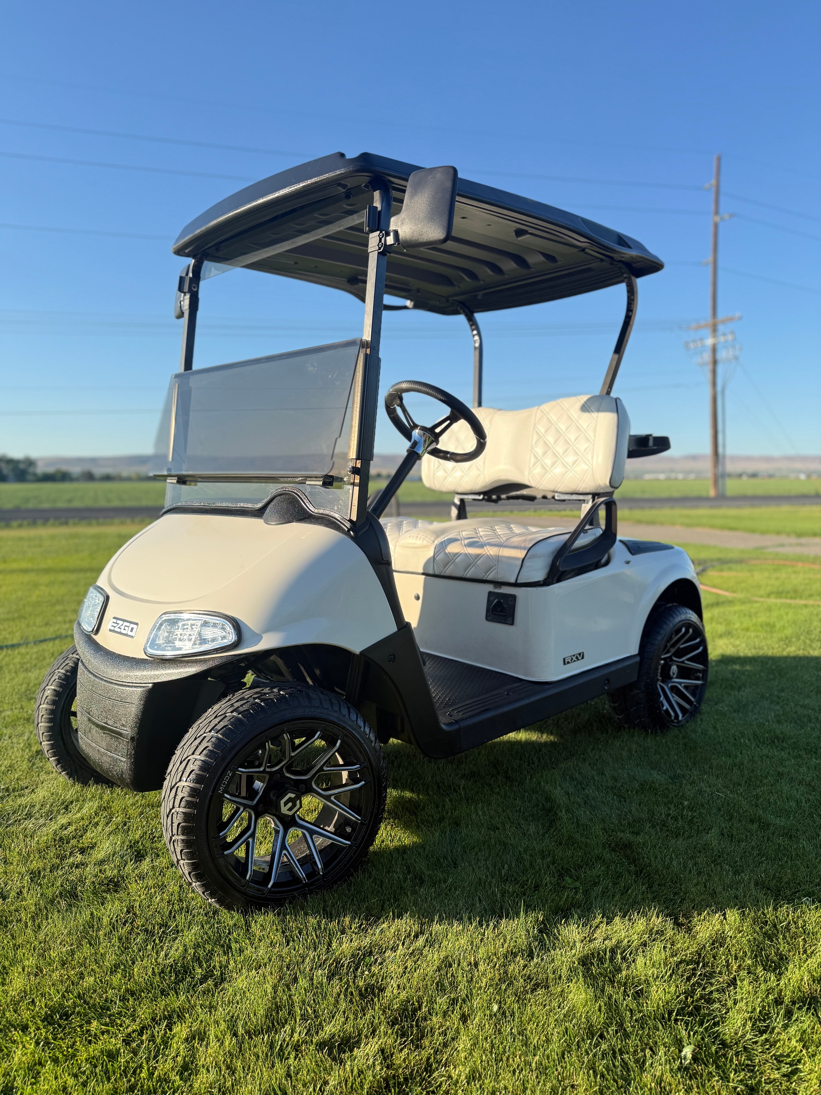 White EZGO RXV custom golf cart with black wheels